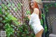 A woman in a white dress standing next to a wooden fence.