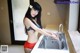 A woman in a bikini washing her hands in a kitchen sink.