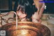 A woman is washing her hands in a copper sink.