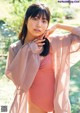 A woman in a pink bodysuit posing for a picture.