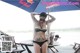 A woman in a bikini standing under an umbrella.