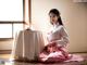 A woman in a pink kimono sitting on the floor next to a table.