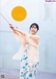 A woman holding an umbrella standing on a beach.