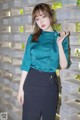 a woman in a green shirt and black skirt posing for a picture